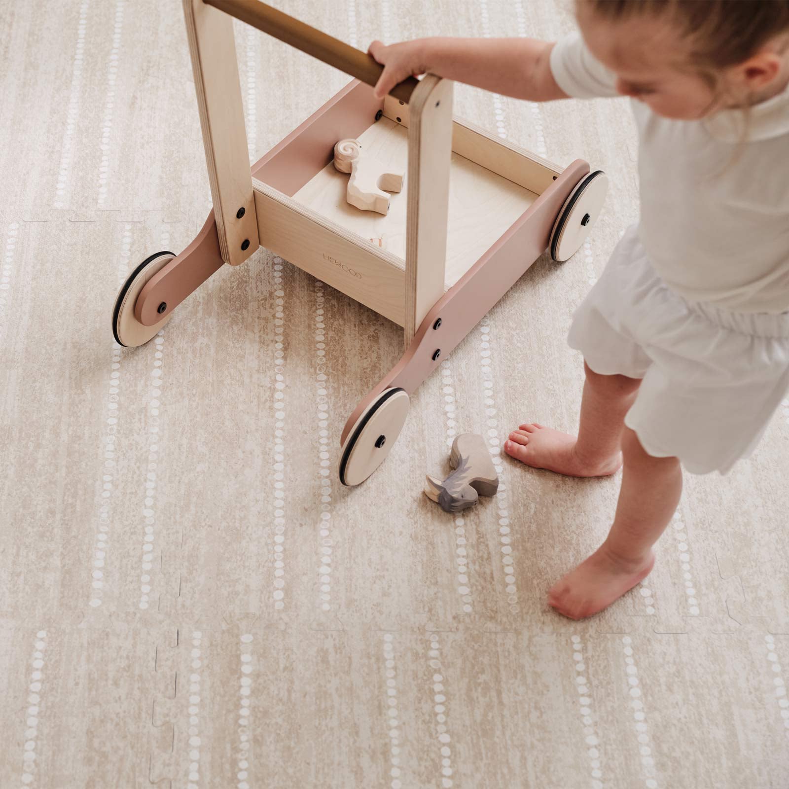 Aspen toast neutral minimal stripe little nomad play mat shown with toddler walking on the mat playing with a wooden walker and horse blocks