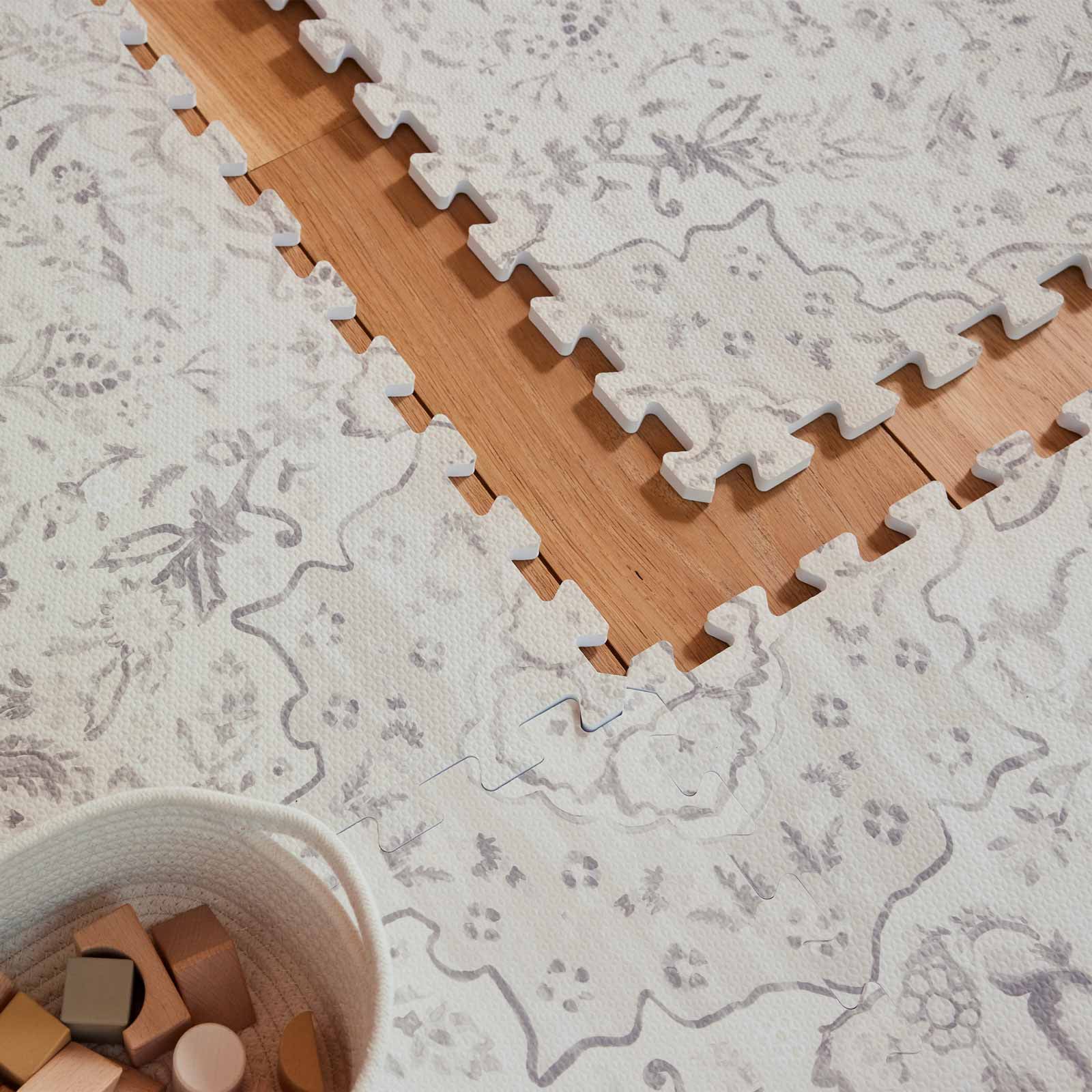 Overhead close up shot of the Emile Latte neutral floral little nomad play mat with one tile exposed to show the puzzle peice edges