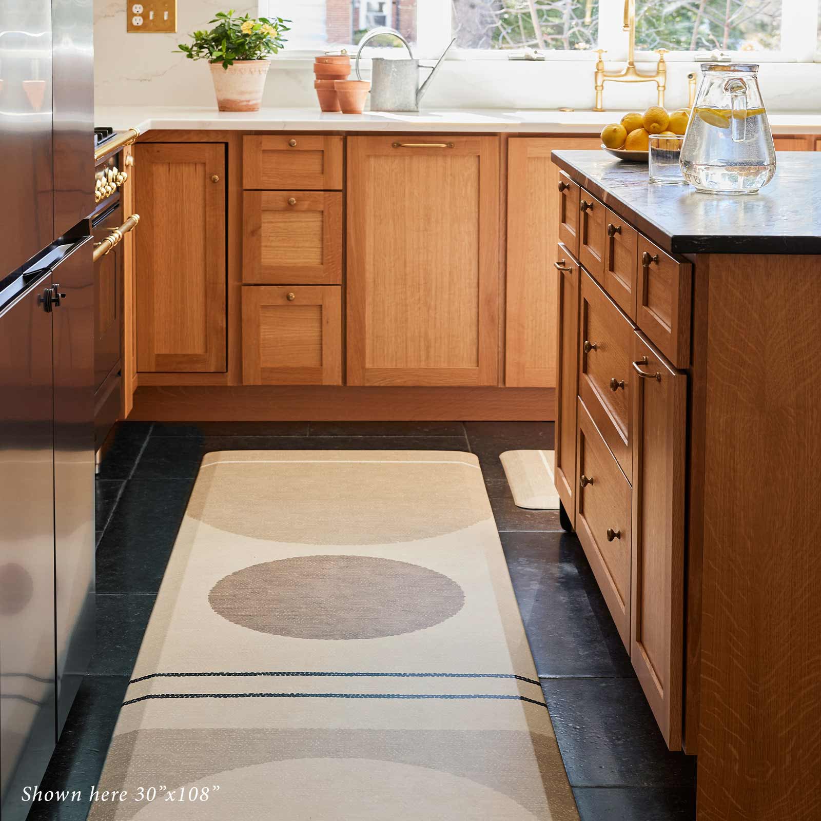 Geode Sesame beige, tan, and brown geometric line print standing mat shown in front of a kitchen island in size 30x108