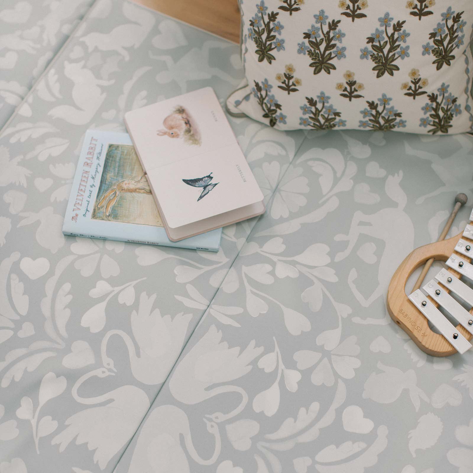 Folklore fog gray and white storybook pattern tumbling mat with pillow, books, xylophone, and pillows laying on the mat