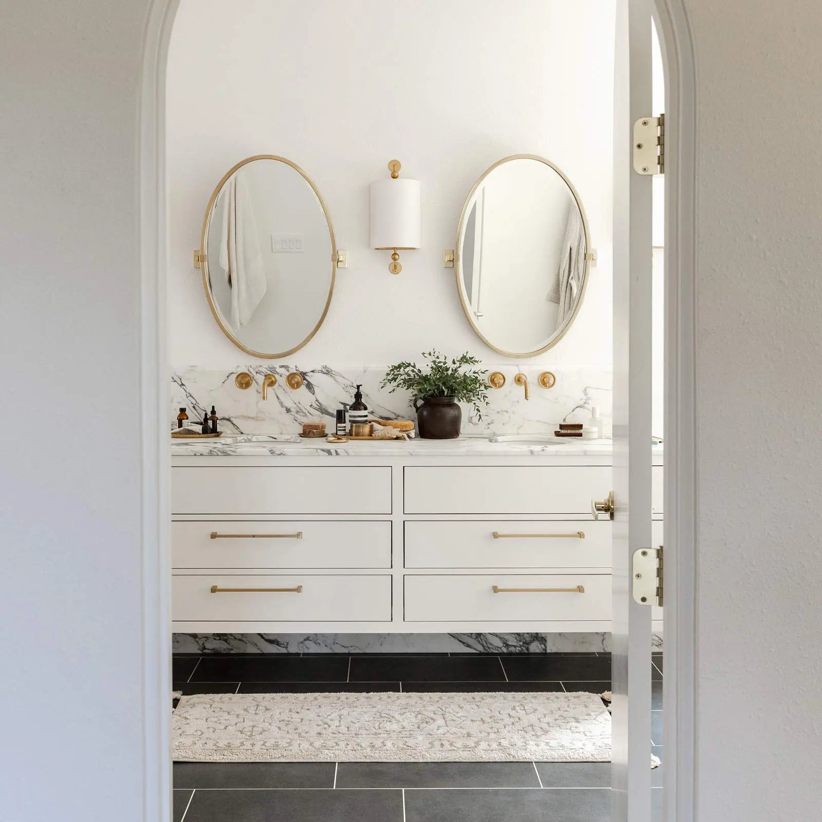 Arden pearl cream and white persian rug pattern bath mat shown in size 21x58 in front of a double vanity bathroom sink, shown from the perspective of the bathroom doorway