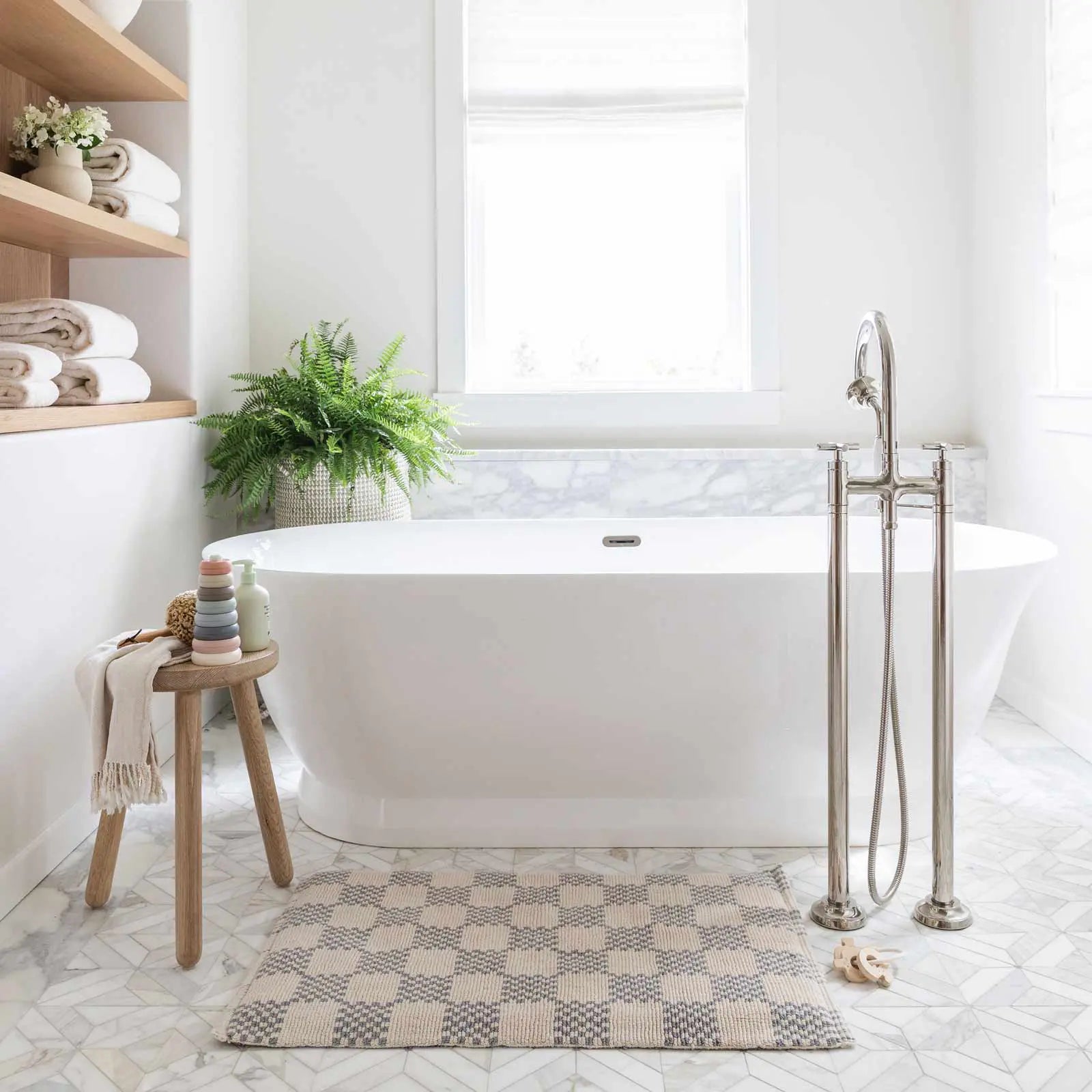 Bath mat in checker harbor gray print in size 21x34 shown in a bathroom in front of a bath tub