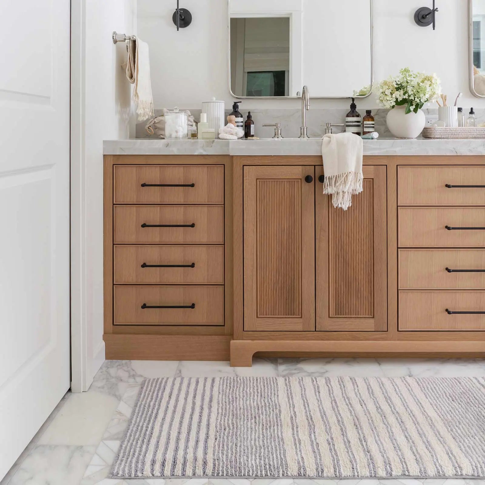 Coastal Nantucket blue and white stripe bath mat in size 21x58 in a bathroom in front of a double vanity sink