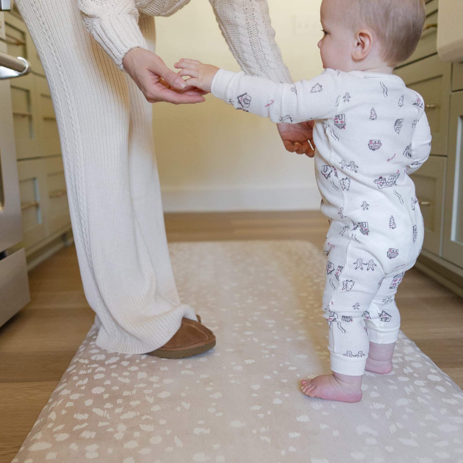 Fawn brown neutral animal print standing mat shown in kitchen with mom and baby wearing christmas pajamas standing on the mat in size 30x108