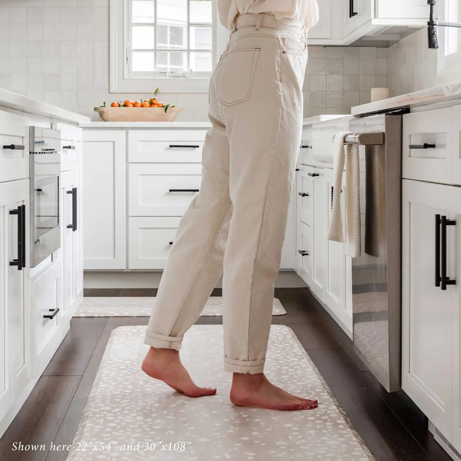 Fawn brown neutral animal print kitchen mat shown in kitchen in sizes 22x54 and 30x108 with woman's legs standing on size 30x108