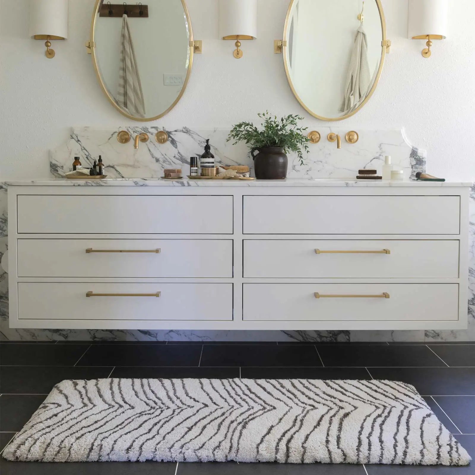 Zelda puffin cream and gray zebra print bath mat shown in a bathroom in size 21x58 in front of a double vanity sink