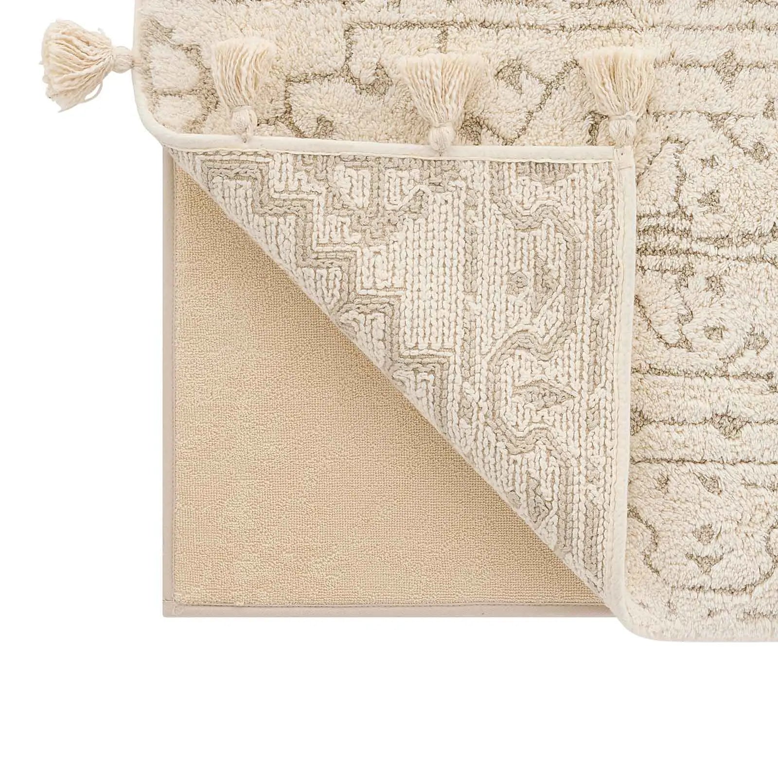 Arden pearl cream and white persian rug pattern bath mat zoomed in on a lifted corner to show the liner underneath