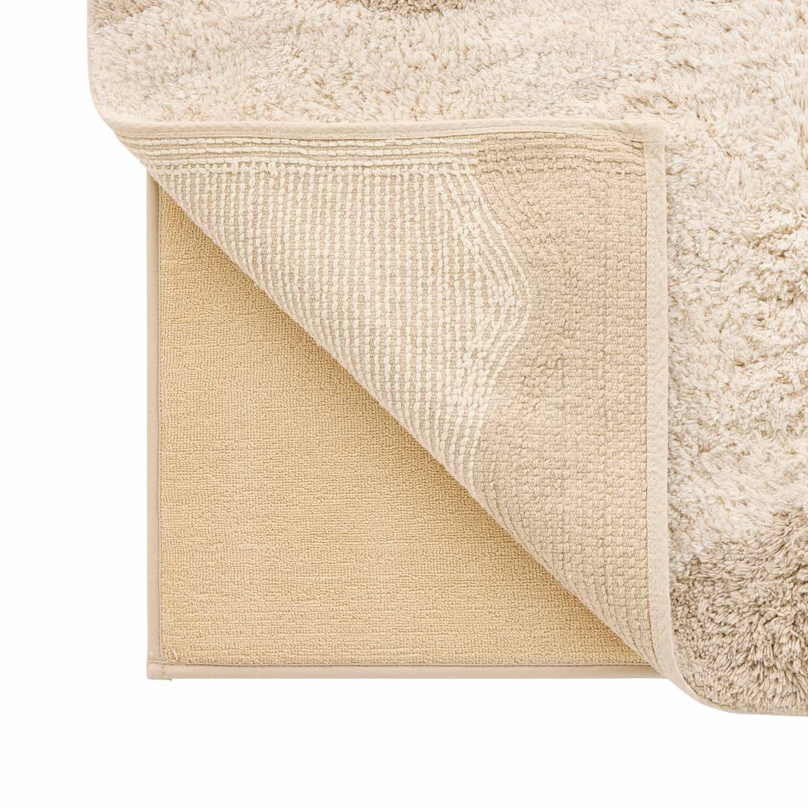 Harper au lait beige scallop print bath mat close up shot of a corner lifted up to show the memory foam liner underneath