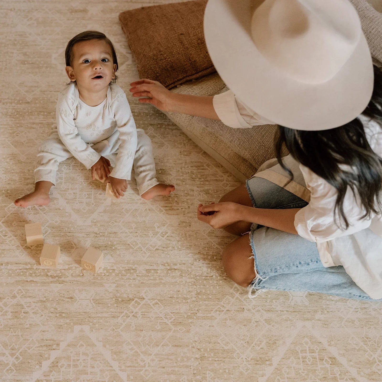 Ula Straw neutral tan minimal boho pattern play mat with pillows and Mom and baby boy playing with wooden blocks