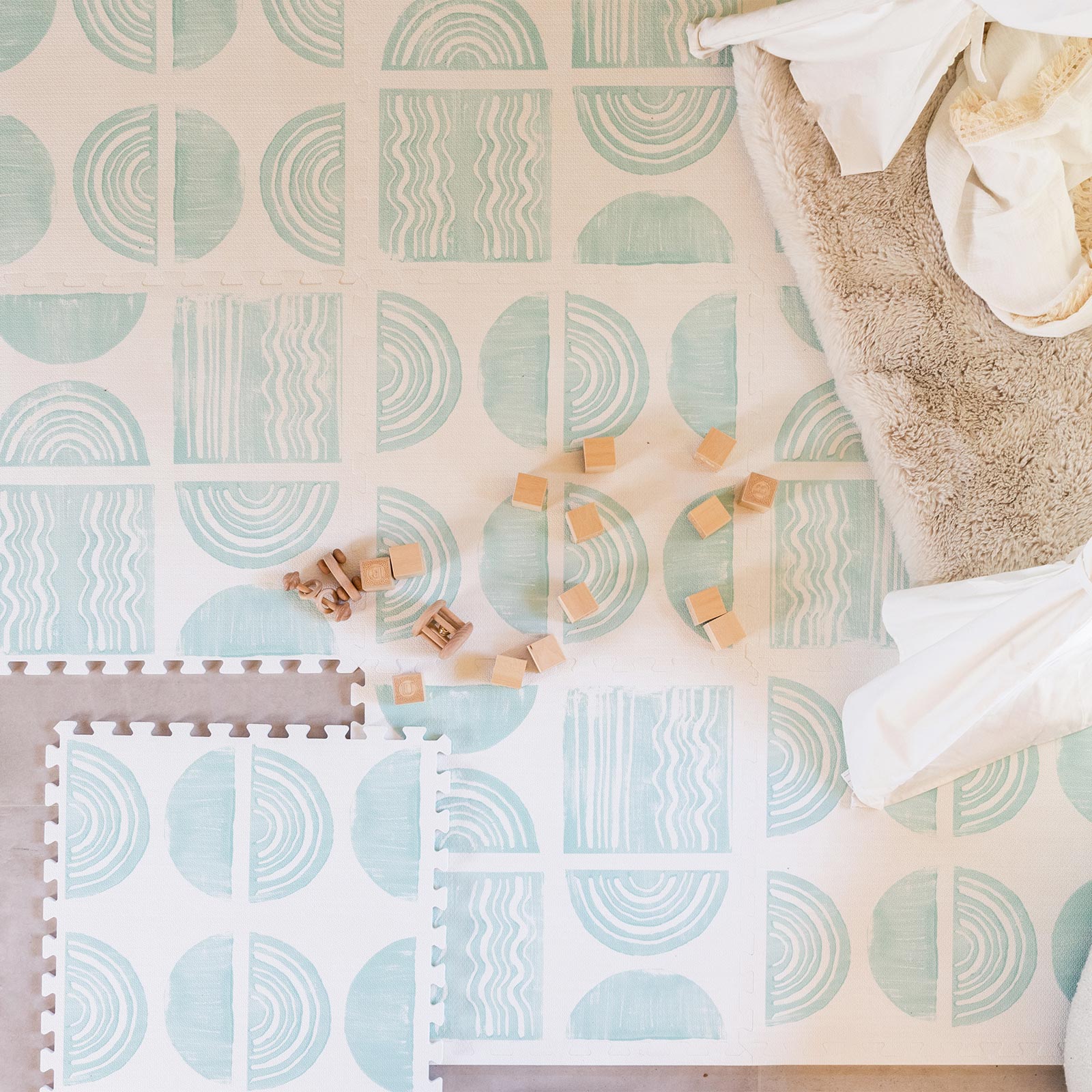 Ada modern minimalist baby play mat in Celadon, pale aqua blue and off white. Shown from above with 1 tile lifted and baby blocks.