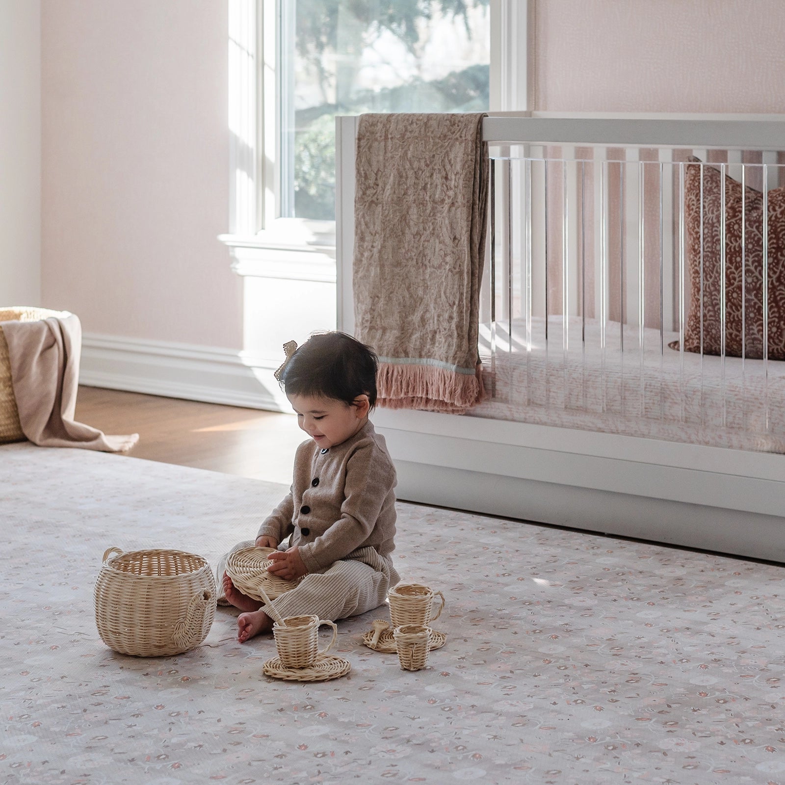 Linen beige and light pink floral baby play mat in nursery with baby sitting playing with tea set