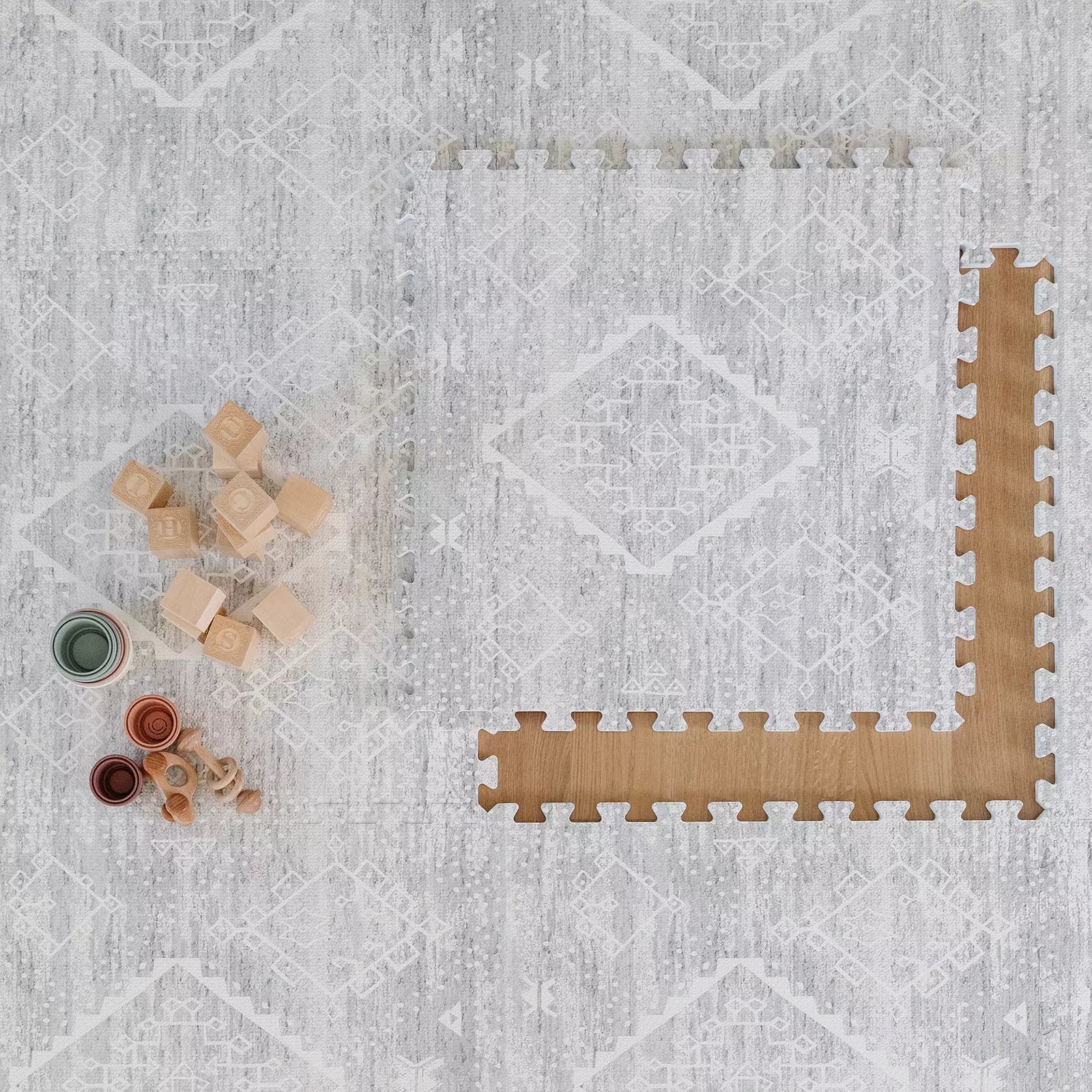 Gray and white minimal boho baby play mat shown with one tile exposed and baby toys 