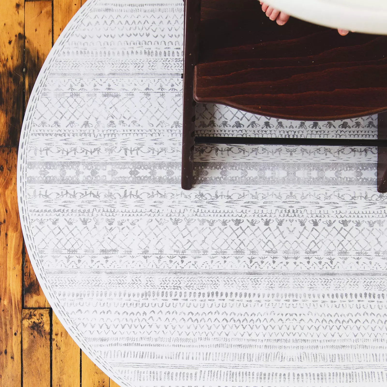 Skipping Stone gray and white striped highchair mat shown under highchair